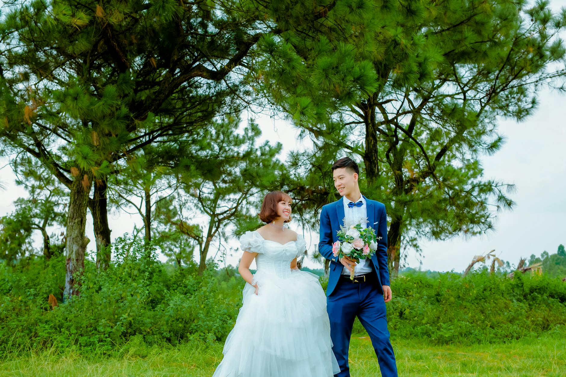 Szczęśliwa para azjatycka na ślubie w plenerze pośród zieleni