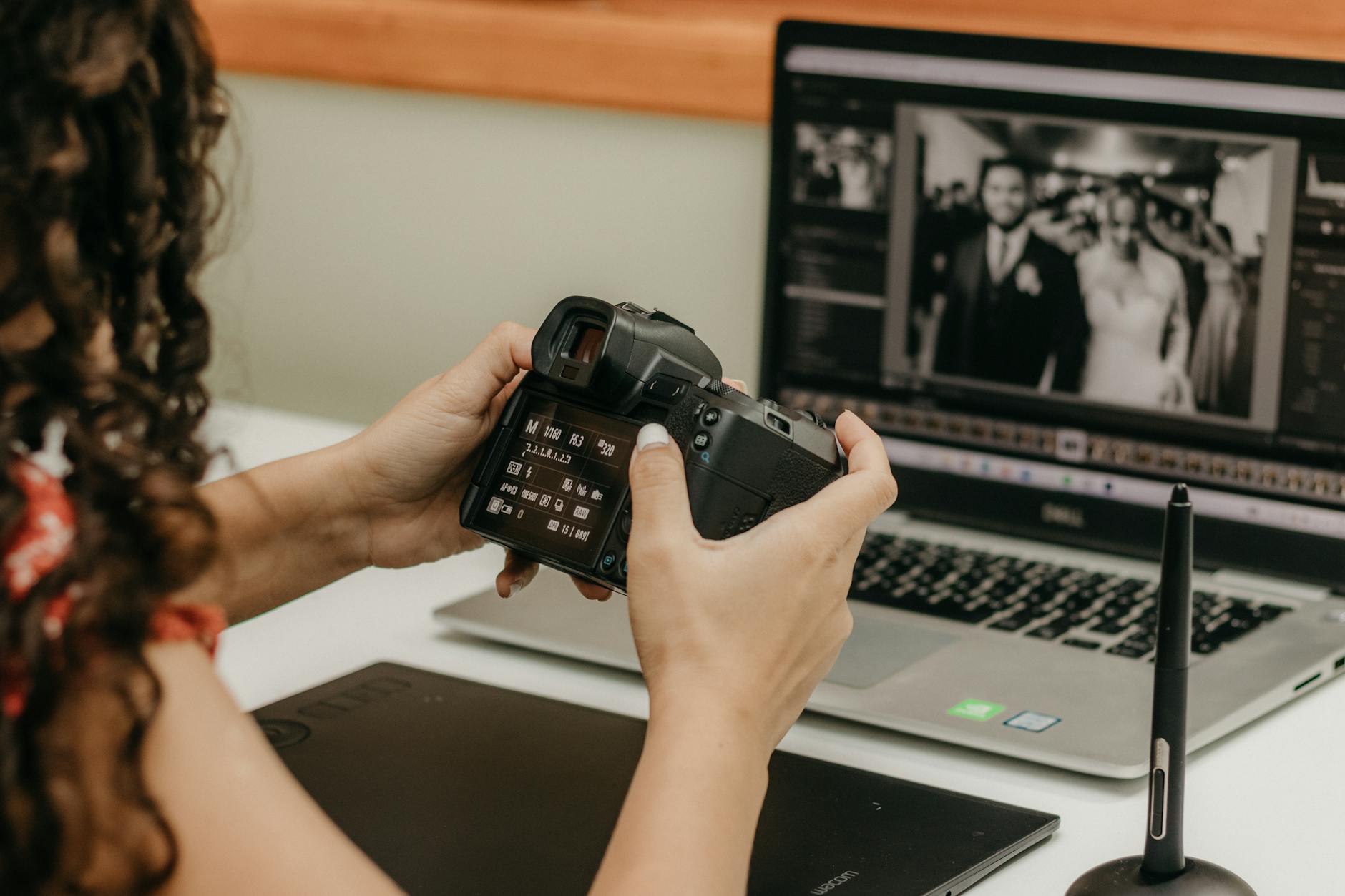 Fotograf przy laptopie edytuje zdjęcia ślubne i sprawdza ustawienia aparatu