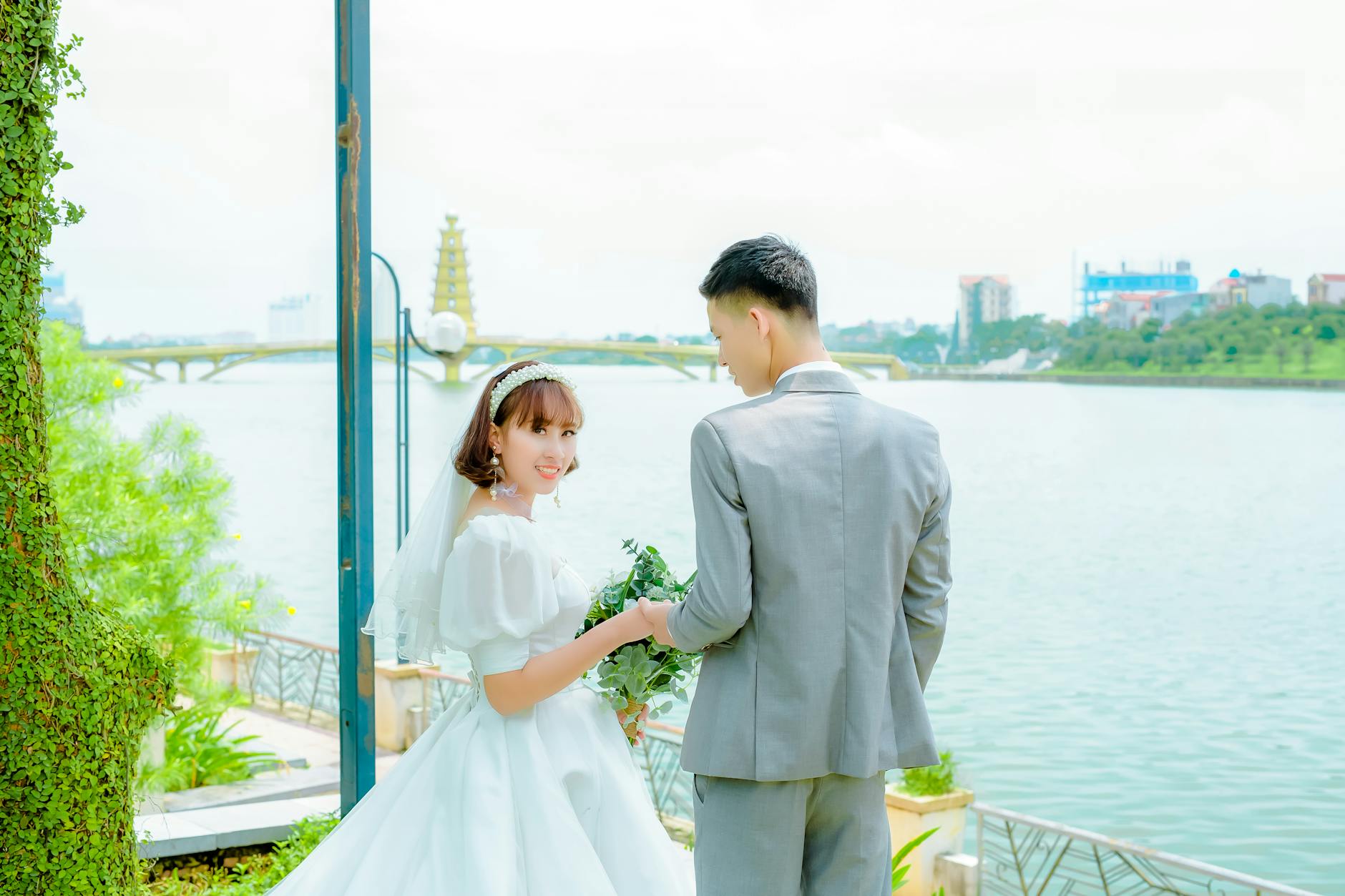 Para młoda trzyma się za ręce nad Wisłą i uśmiecha do obiektywu