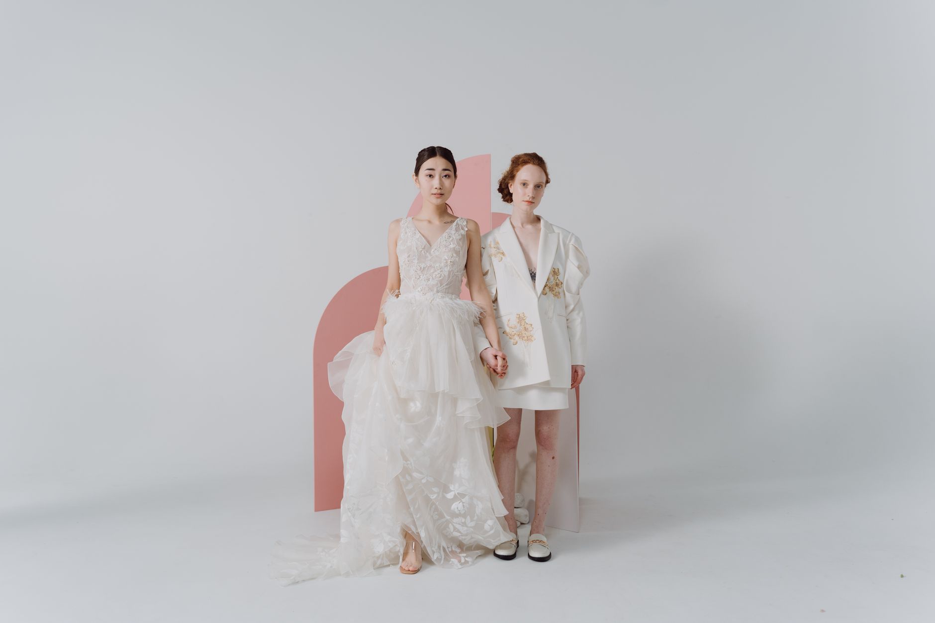 Dwie eleganckie kobiety w ślubnych stylizacjach pozują w studio