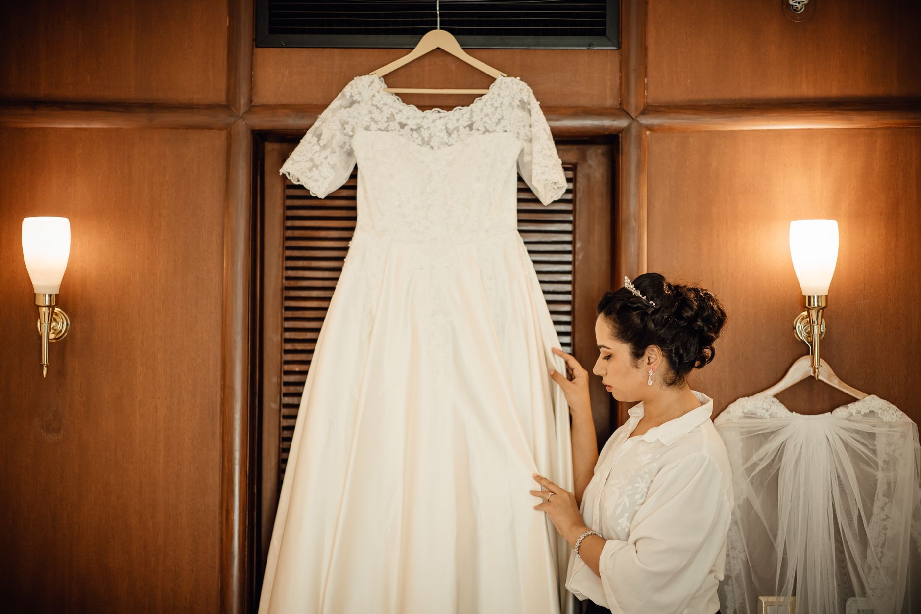 Panna młoda podziwia białą suknię ślubną w eleganckim, drewnianym wnętrzu
