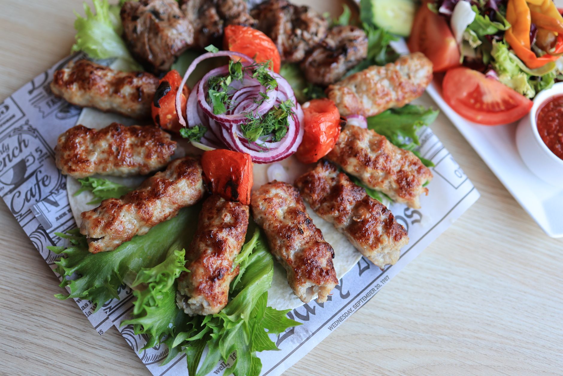 Talerz grillowanych kebabów z warzywami i sosem, gotowy do zamówienia Talerz grillowanych kebabów z warzywami i sosem, gotowy do zamówienia